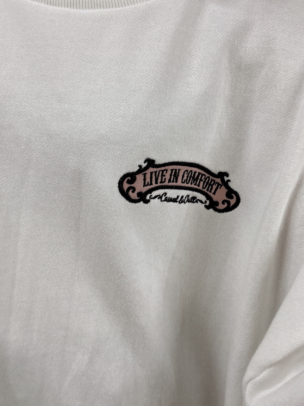 ホワイト系のスウェット、ブラック系のデニムパンツ、ブラック系のブーツを着用したレディースの秋コーディネートの4枚目の写真