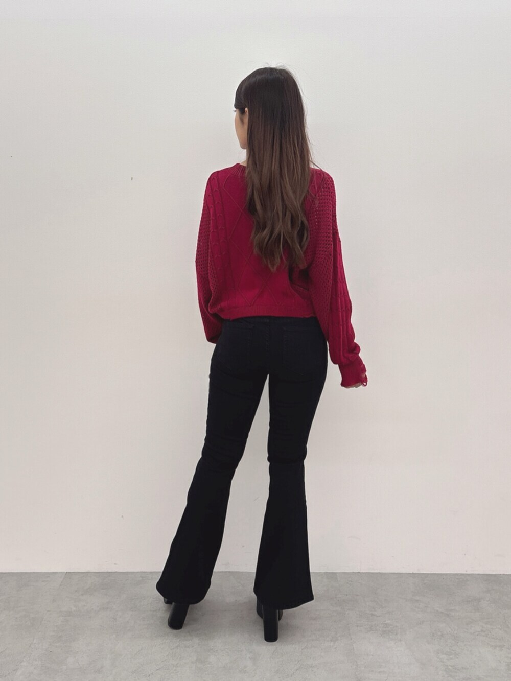 ブラック系のサンダル、レッド系のニット/セーター、ブラック系のデニムパンツを着用したレディースの夏コーディネートの3枚目の写真