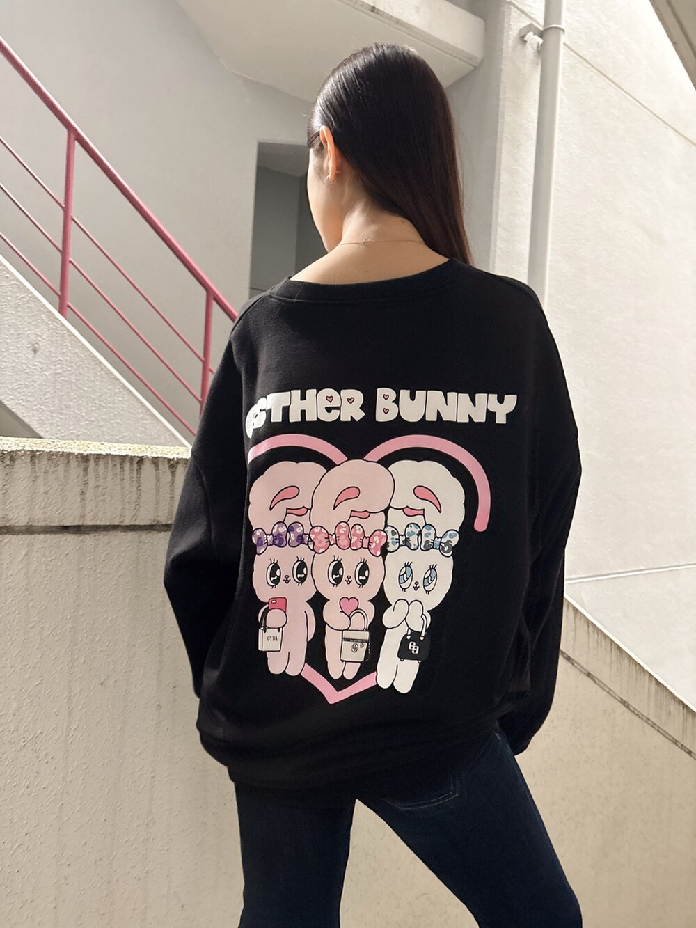 ブラック系のスウェット、ブルー系のデニムパンツ、ブラック系のブーツを着用したレディースの秋コーディネートの5枚目の写真