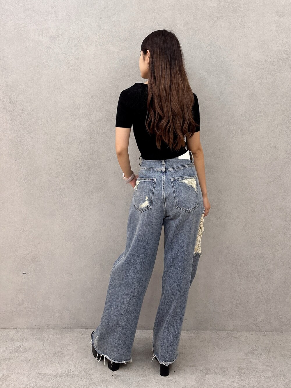 ブルー系のデニムパンツ、ブラック系のサンダル、ブラック系のニット/セーターを着用したレディースの夏コーディネートの3枚目の写真