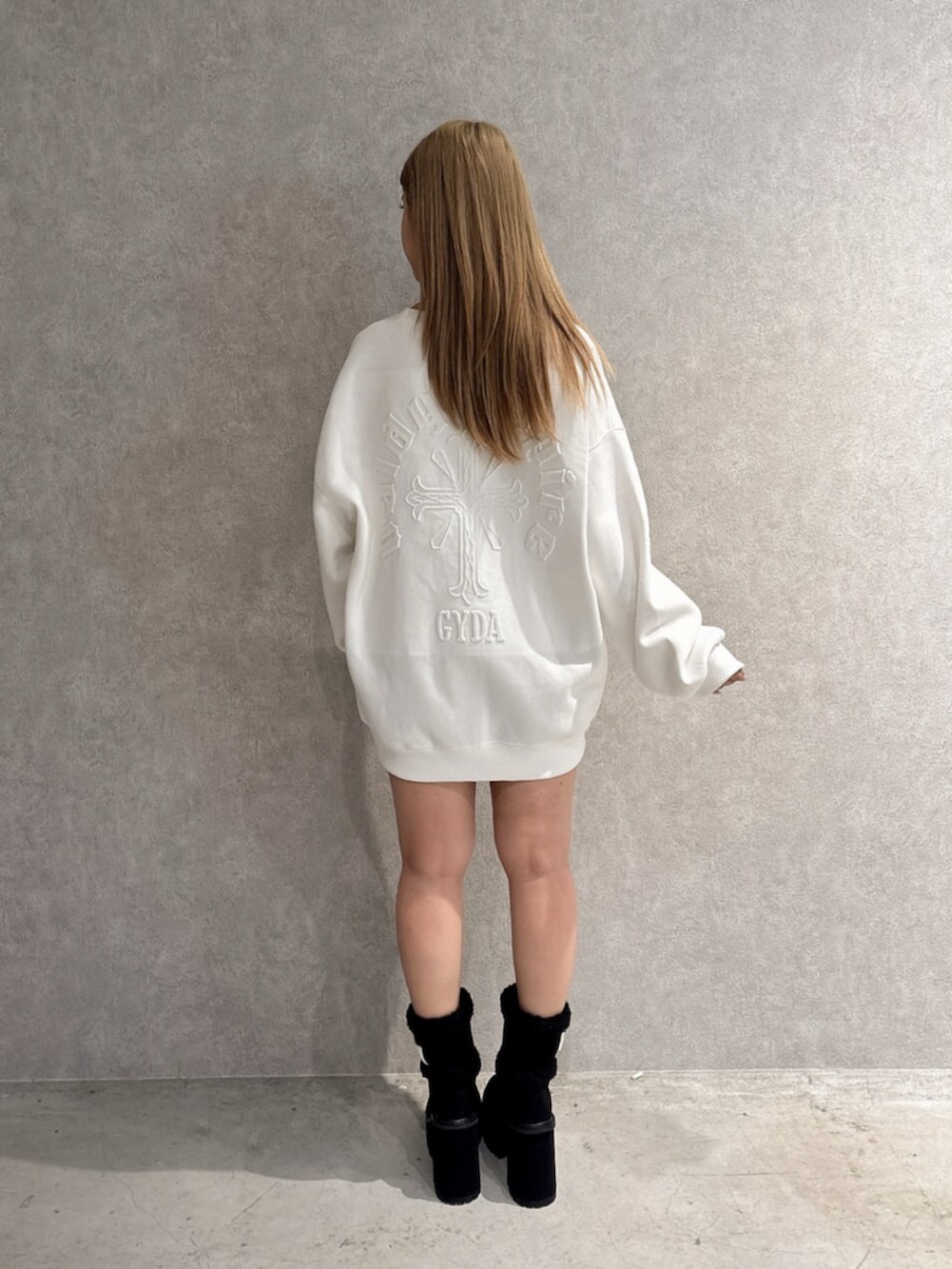 ホワイト系のスウェット、ブルー系のデニムパンツ、ブラック系のブーツを着用したレディースの秋コーディネートの3枚目の写真