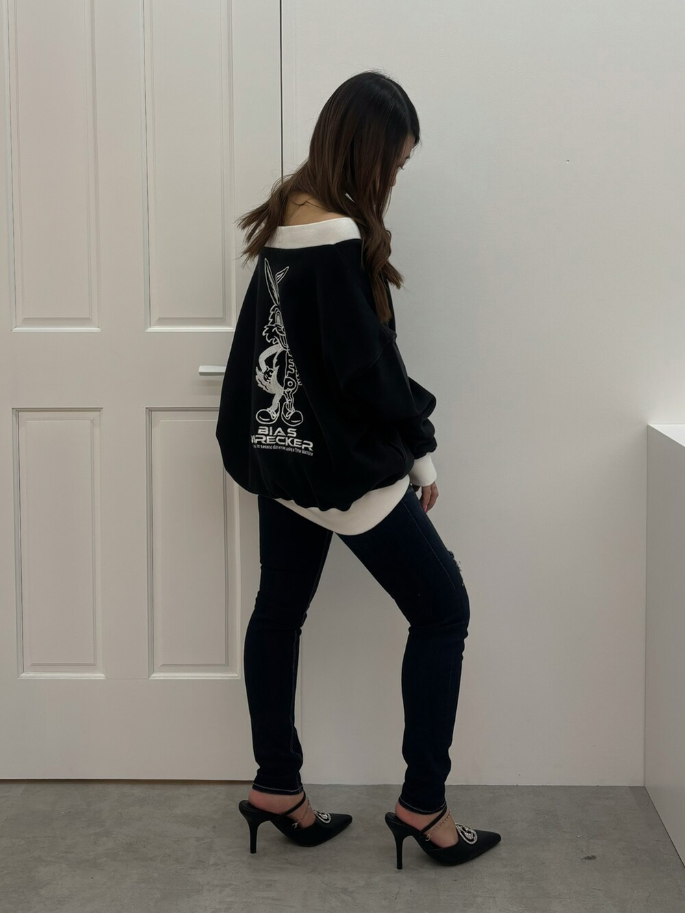 ブラック系のスウェット、ブルー系のデニムパンツ、ブラック系のパンプスを着用したレディースの冬コーディネートの2枚目の写真