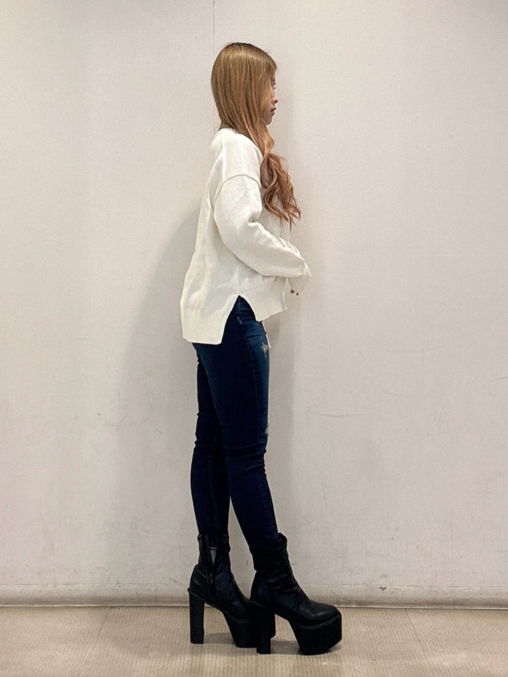 ブラック系のブーツ、ブルー系のデニムパンツ、ホワイト系のニット/セーターを着用したレディースの春コーディネートの2枚目の写真