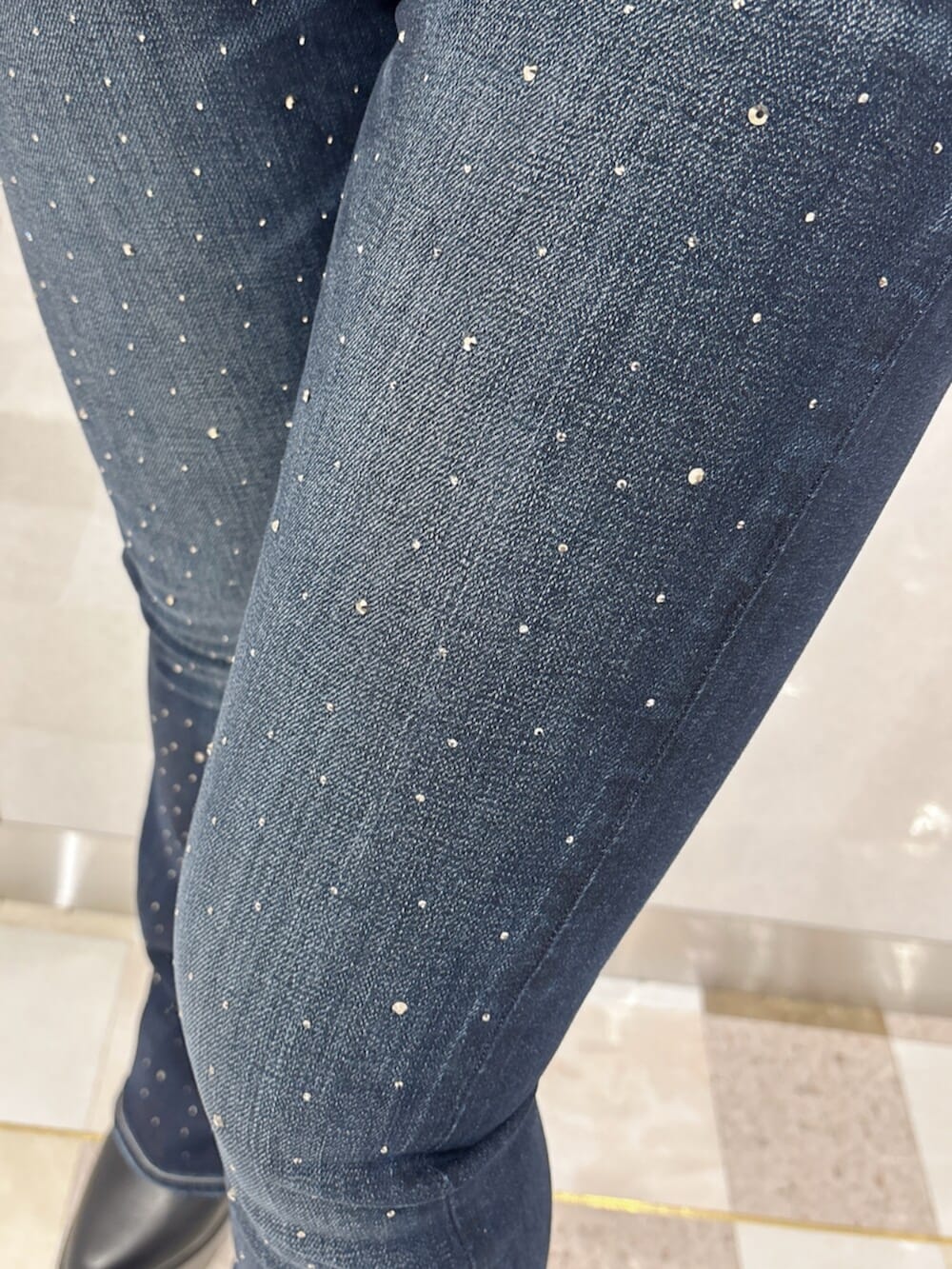 ブラック系のブーツ、ホワイト系のニット/セーター、ブルー系のデニムパンツを着用したレディースの秋コーディネートの6枚目の写真