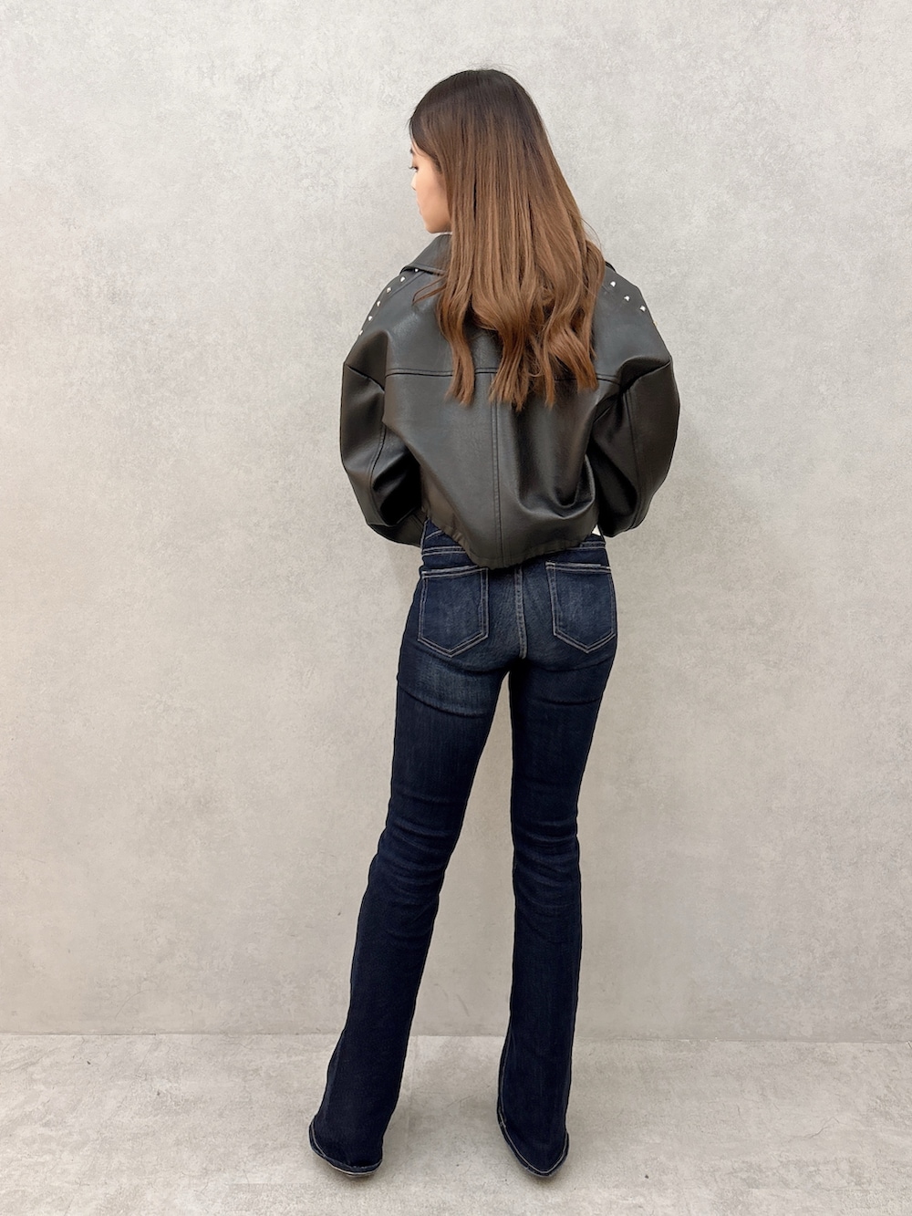 ブラック系のニット/セーター、ブラック系のライダースジャケット、ブルー系のデニムパンツを着用したレディースの冬コーディネートの3枚目の写真