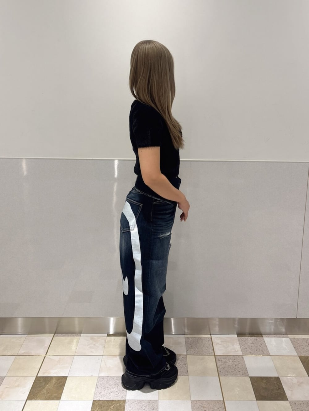 ブラック系のニット/セーター、ブルー系のデニムパンツ、ブラック系のスニーカーを着用したレディースの夏コーディネートの2枚目の写真