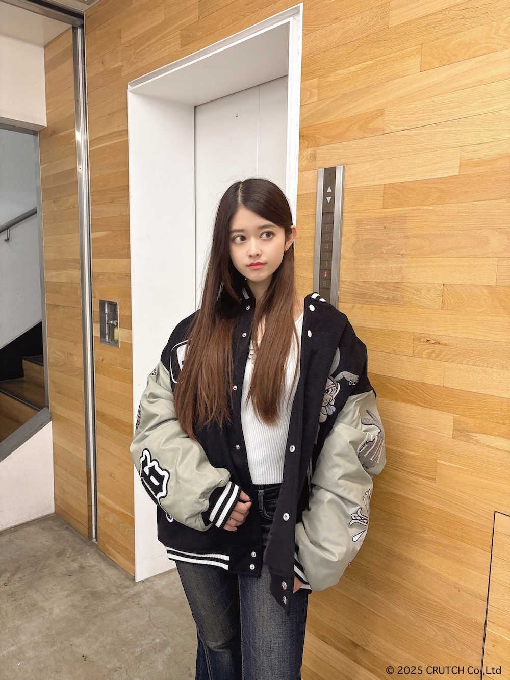 ブラック系のスタジャン、ホワイト系のニット/セーター、ブルー系のデニムパンツを着用したレディースの秋コーディネートの4枚目の写真