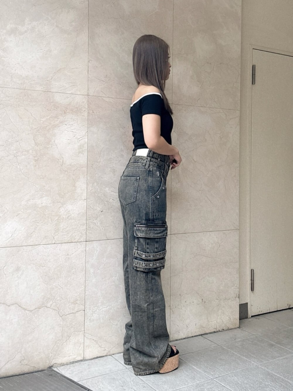ブルー系のデニムパンツ、ブラック系のサンダル、ブラック系のTシャツ/カットソーを着用したレディースの夏コーディネートの2枚目の写真
