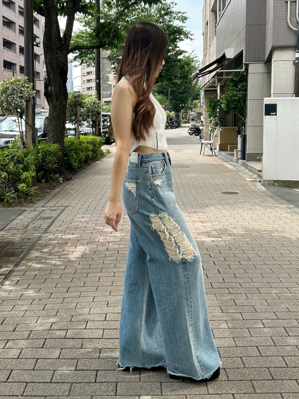 ホワイト系のニット/セーター、ブルー系のデニムパンツ、ブラック系のサンダルを着用したレディースの夏コーディネートの2枚目の写真