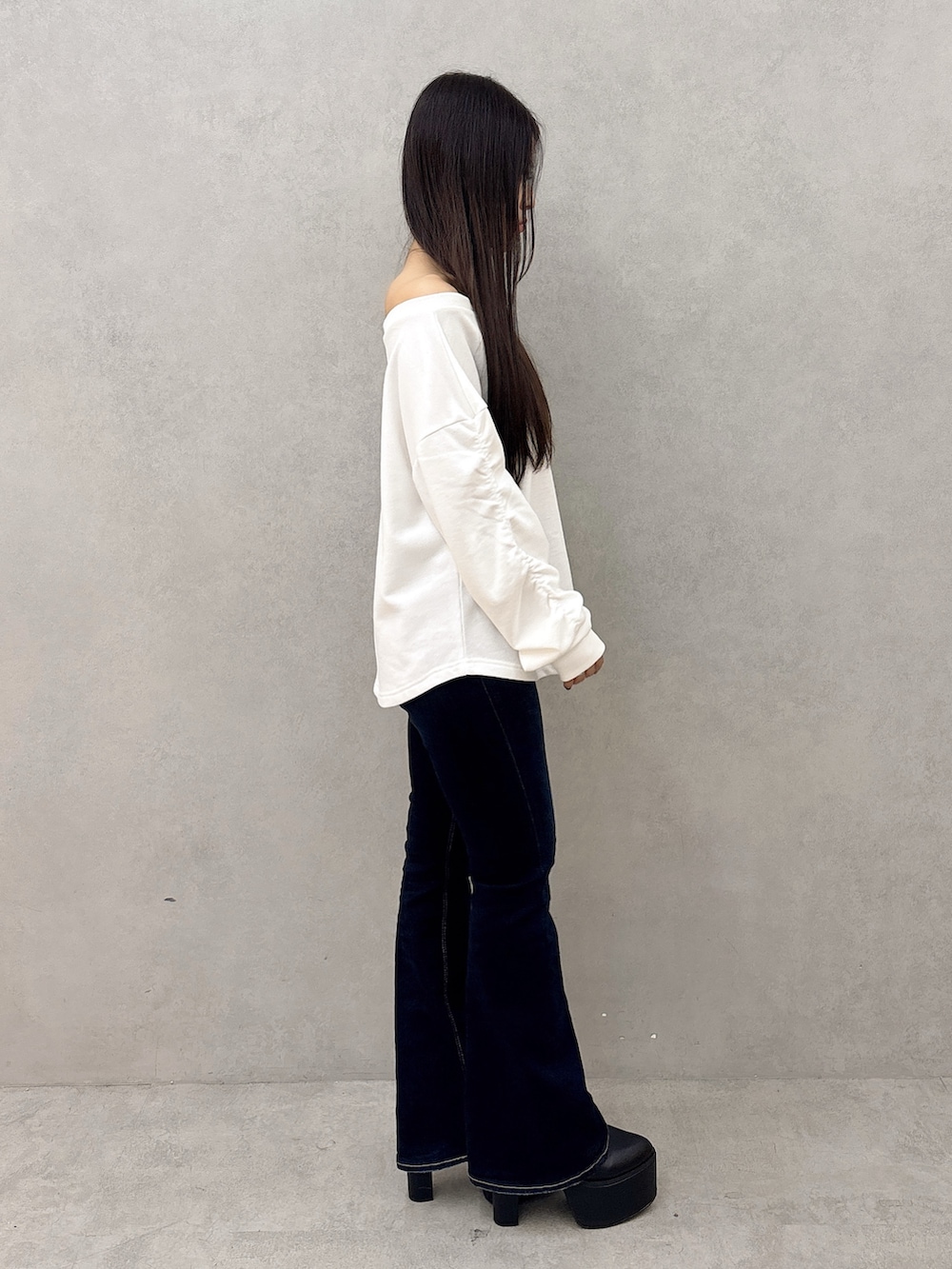 ホワイト系のスウェット、ブルー系のデニムパンツ、ブラック系のブーツを着用したレディースの秋コーディネートの2枚目の写真