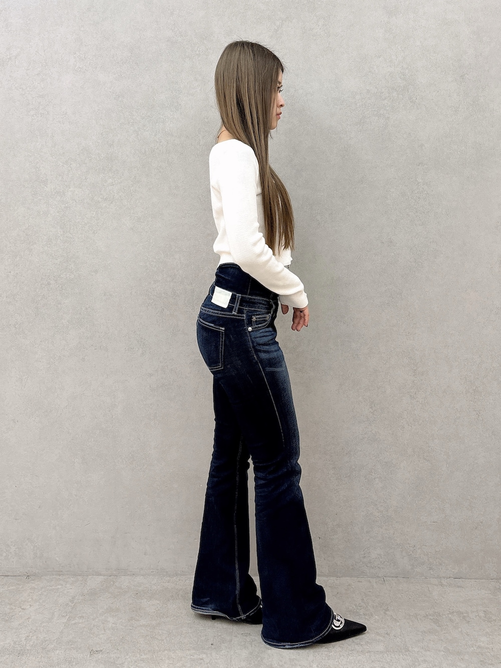 ホワイト系のニット/セーター、ブルー系のデニムパンツ、ブラック系のパンプスを着用したレディースの春コーディネートの2枚目の写真