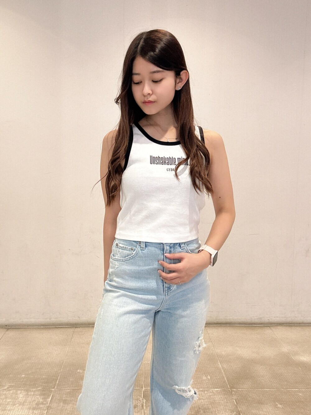 ブラック系のスニーカー、ホワイト系のタンクトップ、ブルー系のデニムパンツを着用したレディースの春コーディネートの4枚目の写真