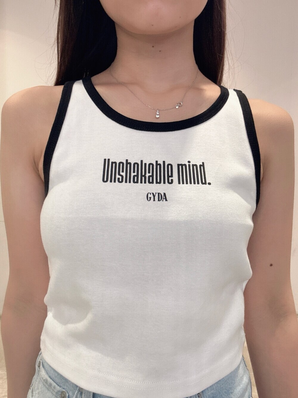 ブラック系のスニーカー、ホワイト系のタンクトップ、ブルー系のデニムパンツを着用したレディースの春コーディネートの5枚目の写真