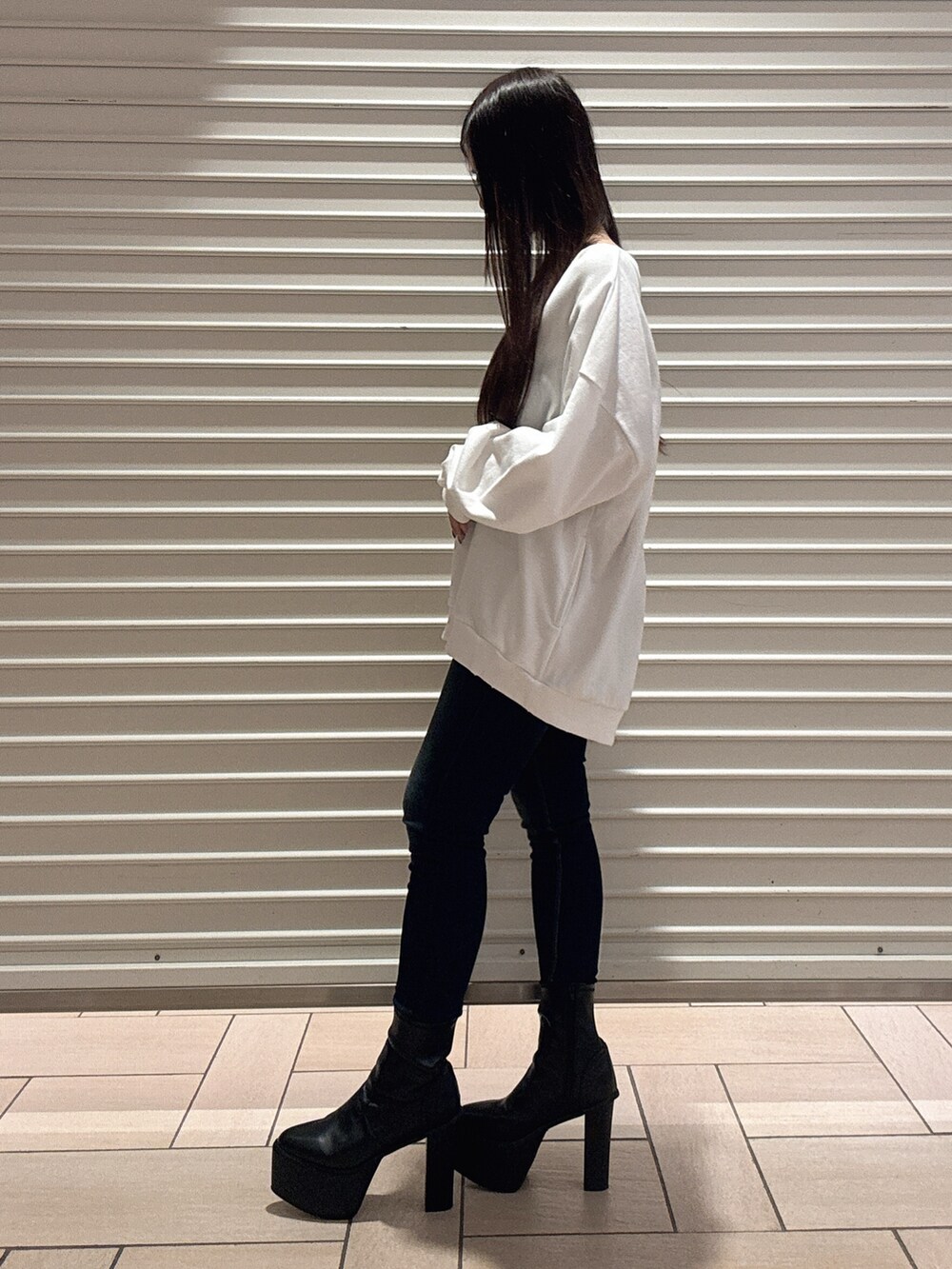 ホワイト系のスウェット、ブルー系のデニムパンツ、ブラック系のブーツを着用したレディースの秋コーディネートの2枚目の写真