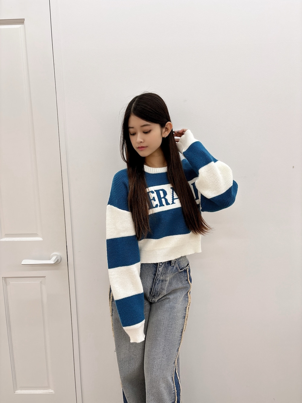 ブルー系のニット/セーター、ブルー系のデニムパンツ、ブラック系のブーツを着用したレディースの秋コーディネートの4枚目の写真