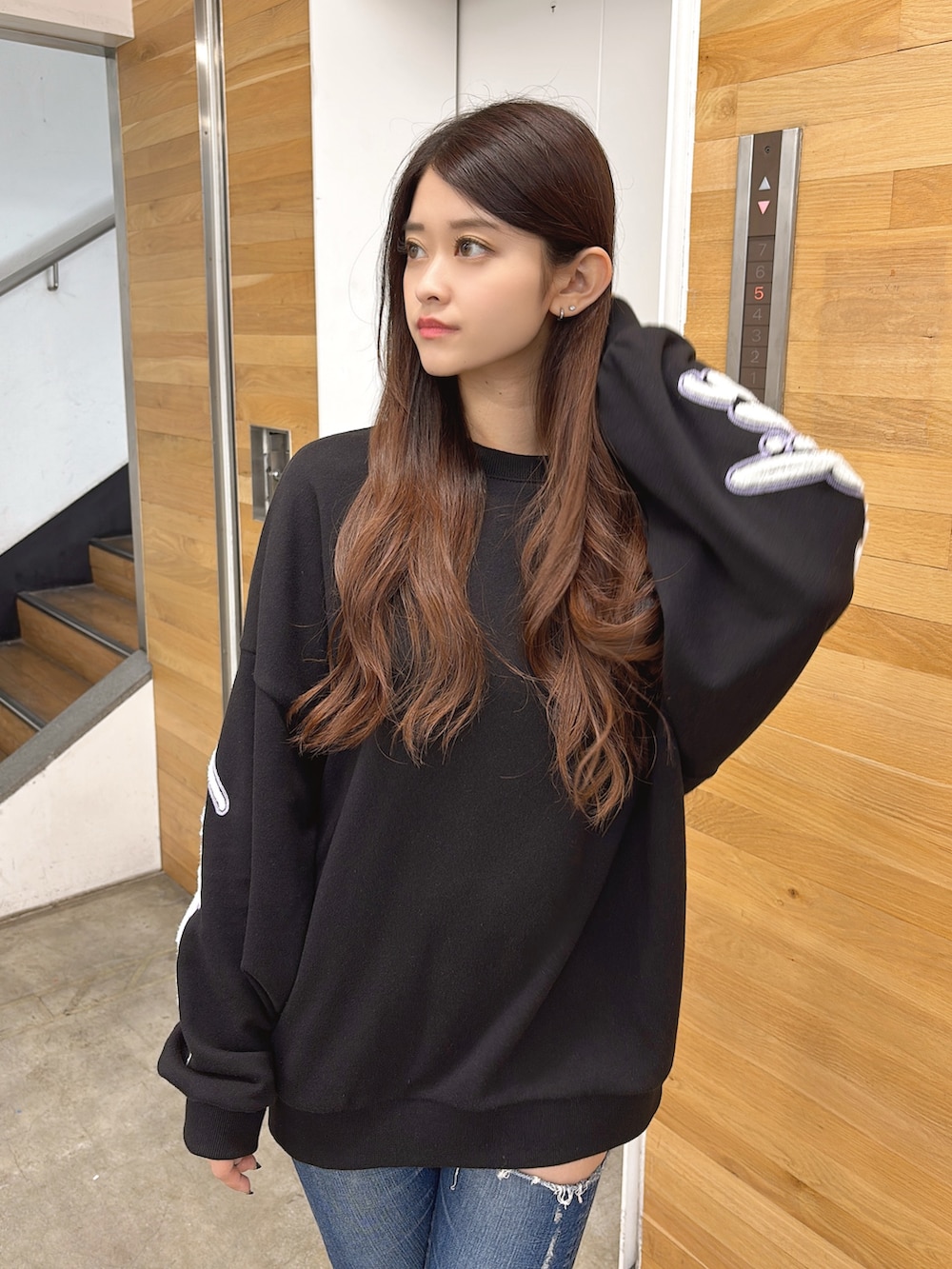 ブラック系のスウェット、ブルー系のデニムパンツ、ブラック系のブーツを着用したレディースの夏コーディネートの4枚目の写真