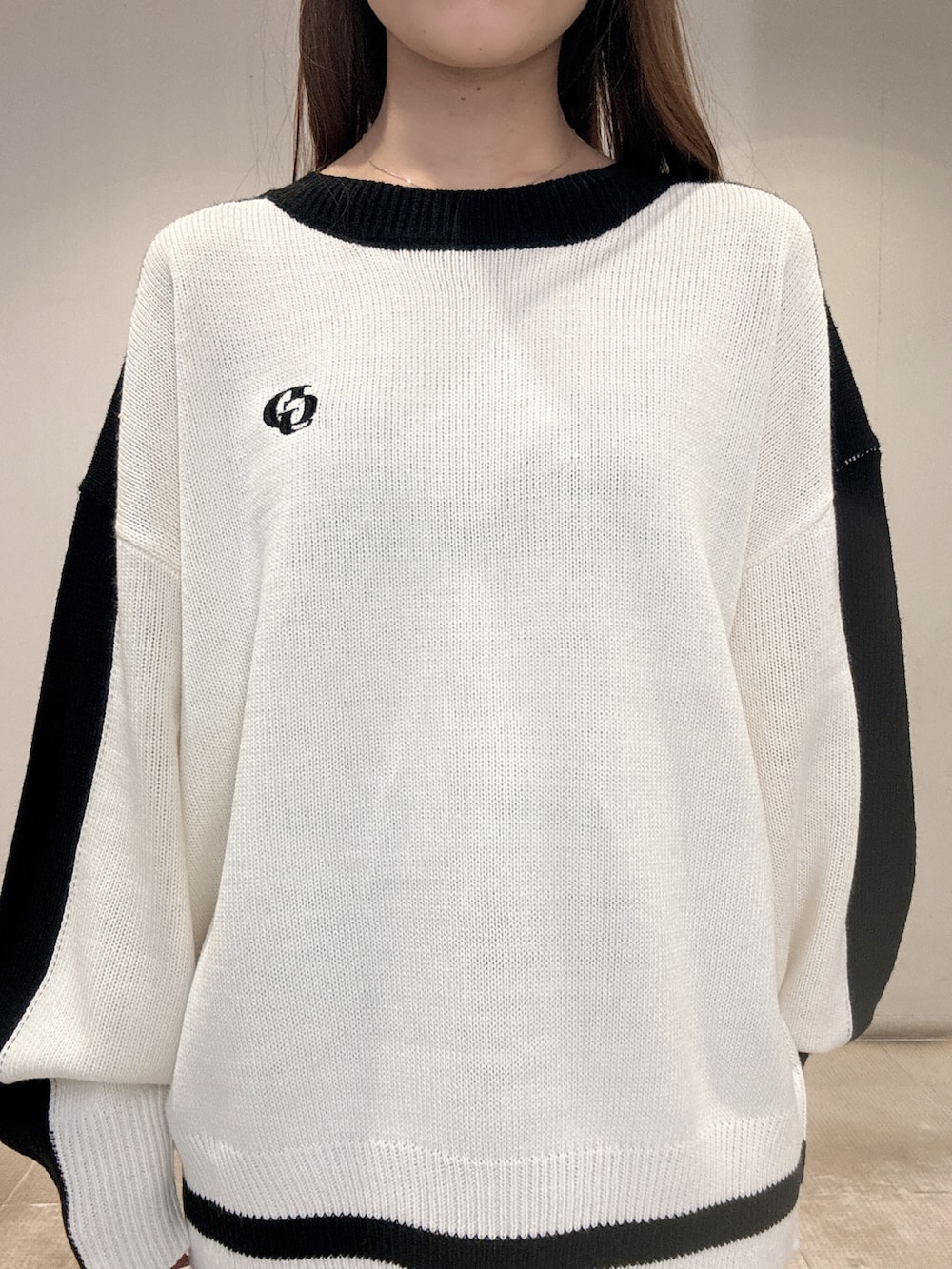 ホワイト系のニット/セーター、ブラック系のデニムパンツ、ブラック系のパンプスを着用したレディースの春コーディネートの6枚目の写真