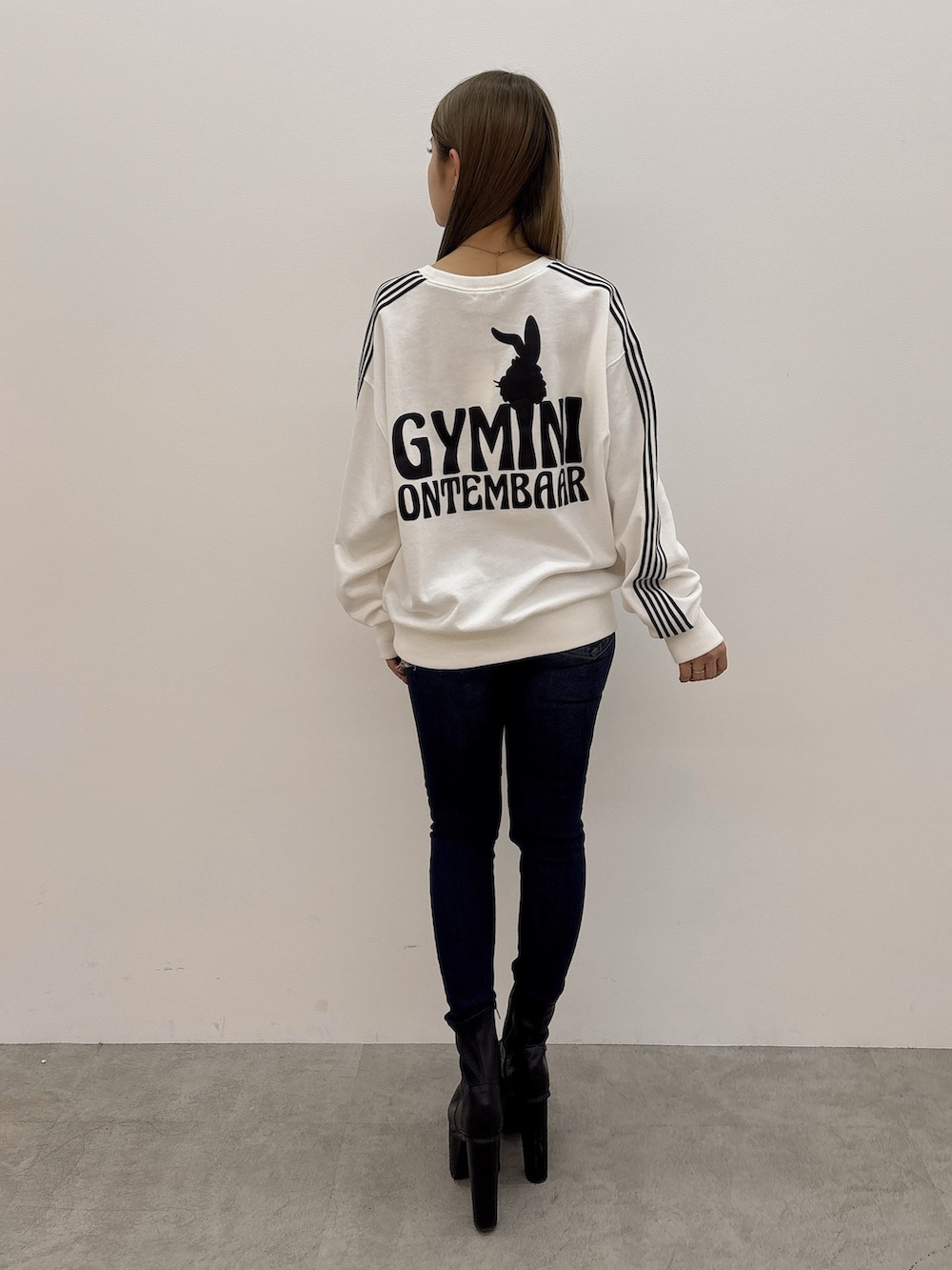 ホワイト系のスウェット、ブルー系のデニムパンツ、ブラック系のブーツを着用したレディースの冬コーディネートの3枚目の写真