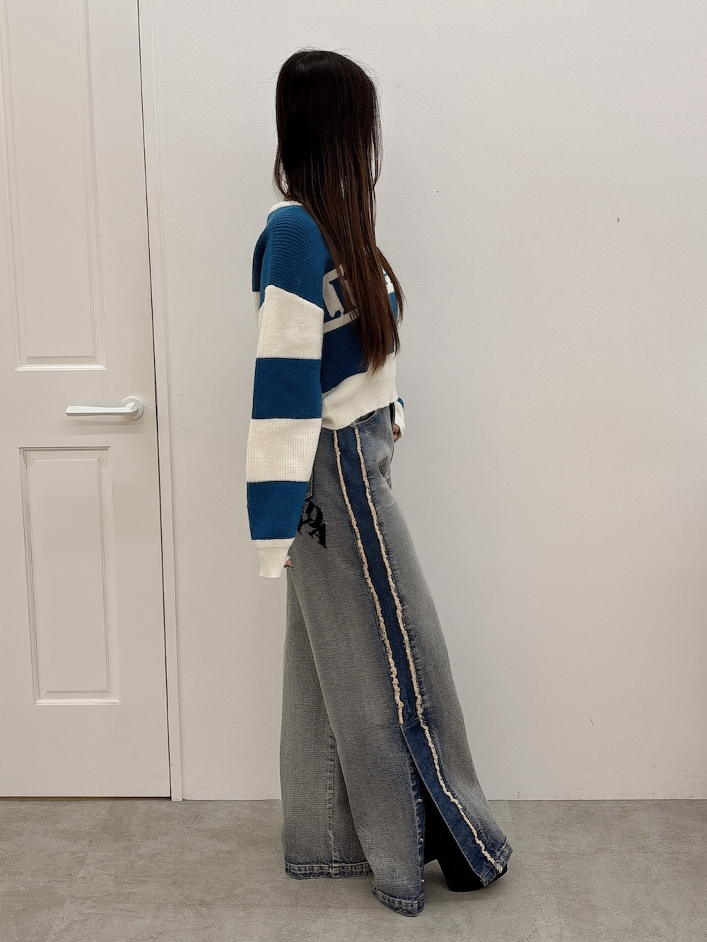 ブルー系のニット/セーター、ブルー系のデニムパンツ、ブラック系のブーツを着用したレディースの秋コーディネートの2枚目の写真