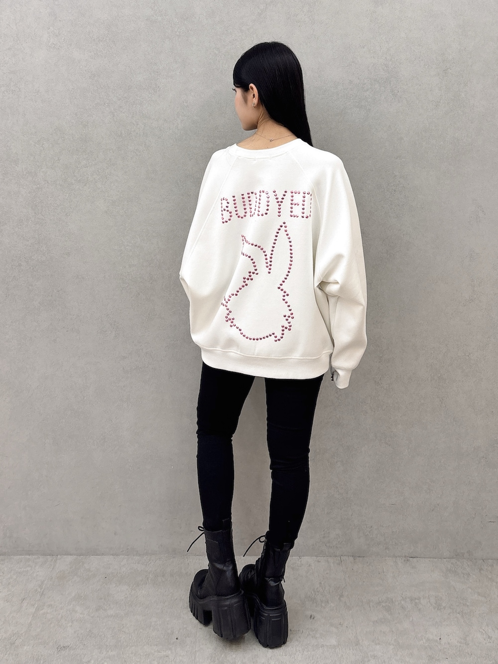 ホワイト系のスウェット、ブラック系のデニムパンツ、ブラック系のブーツを着用したレディースの冬コーディネートの3枚目の写真