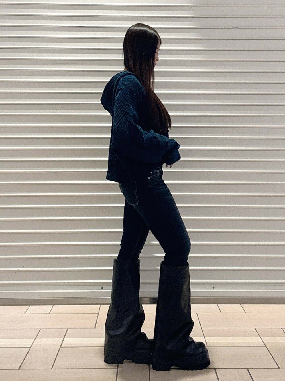 ブルー系のニット/セーター、ブルー系のデニムパンツ、ブラック系のブーツを着用したレディースの秋コーディネートの2枚目の写真