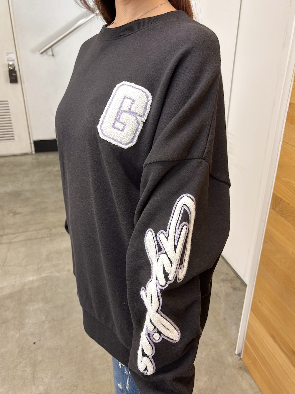 ブラック系のスウェット、ブルー系のデニムパンツ、ブラック系のブーツを着用したレディースの夏コーディネートの5枚目の写真