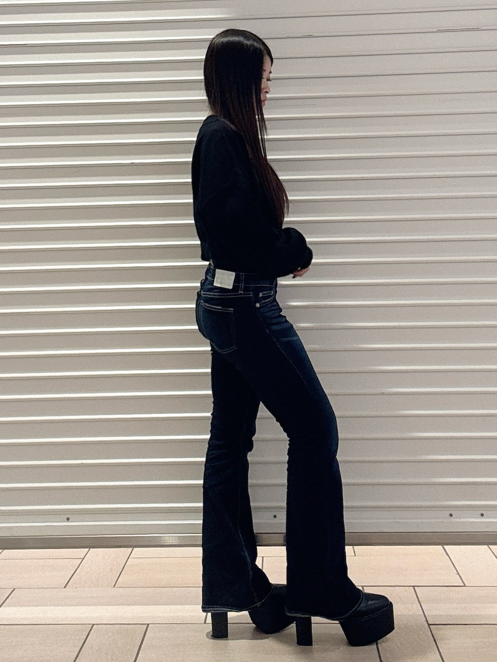 ブラック系のニット/セーター、ブルー系のデニムパンツ、ブラック系のブーツを着用したレディースの秋コーディネートの3枚目の写真