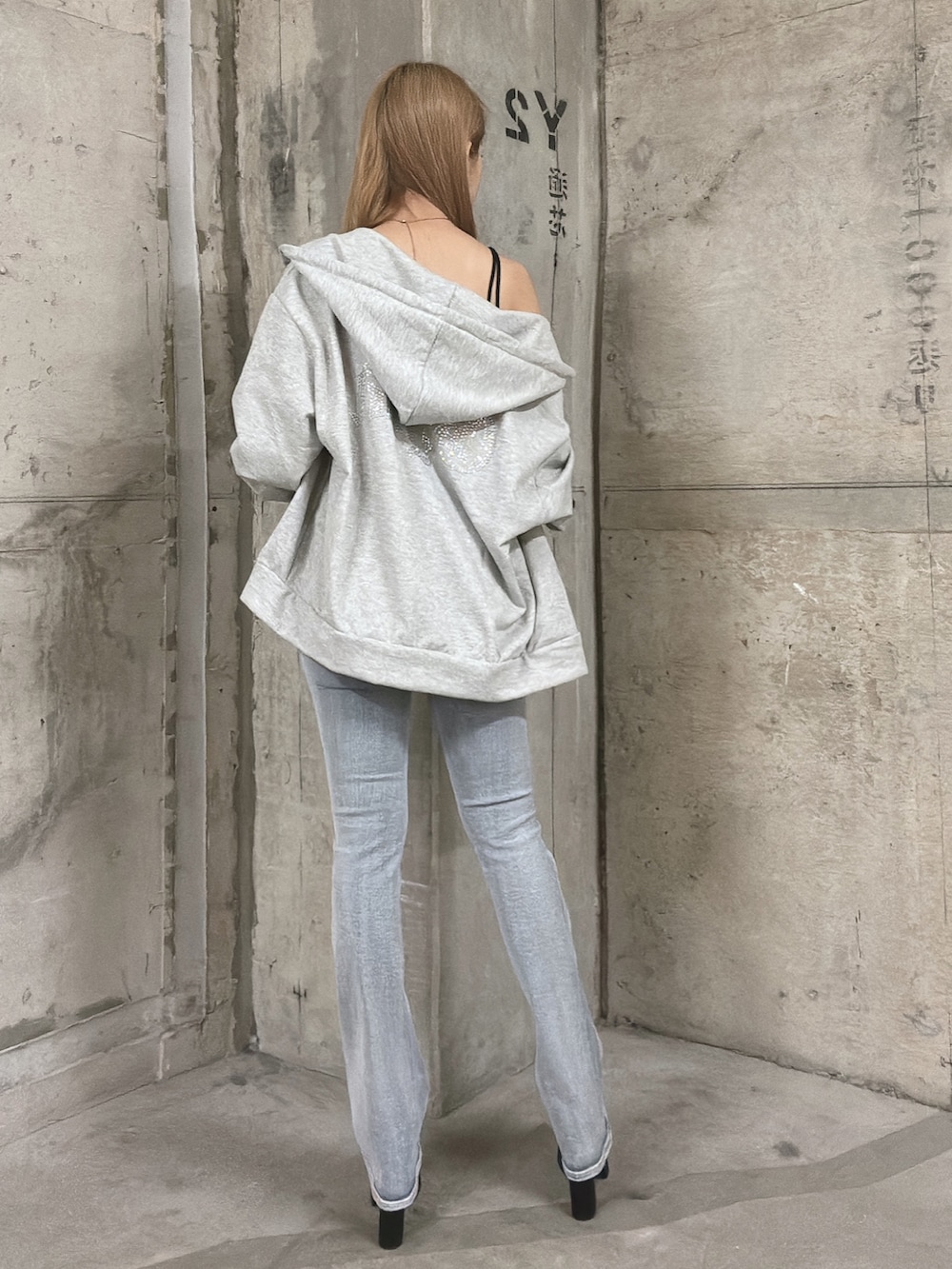 グレー系のパーカー、ブルー系のデニムパンツ、ブラック系のサンダルを着用したレディースの秋コーディネートの3枚目の写真