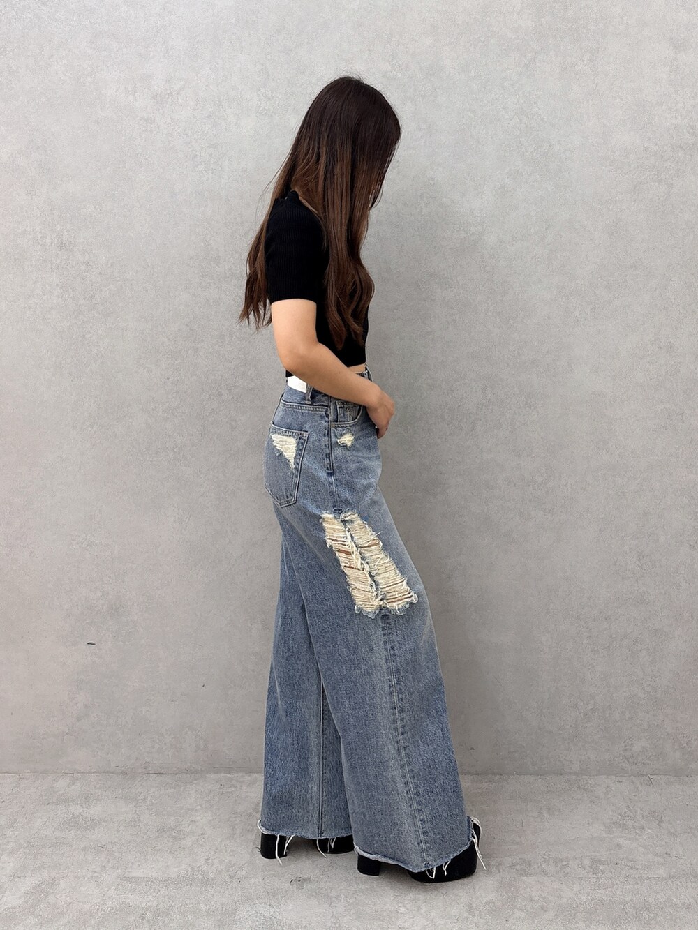 ブルー系のデニムパンツ、ブラック系のサンダル、ブラック系のニット/セーターを着用したレディースの夏コーディネートの2枚目の写真