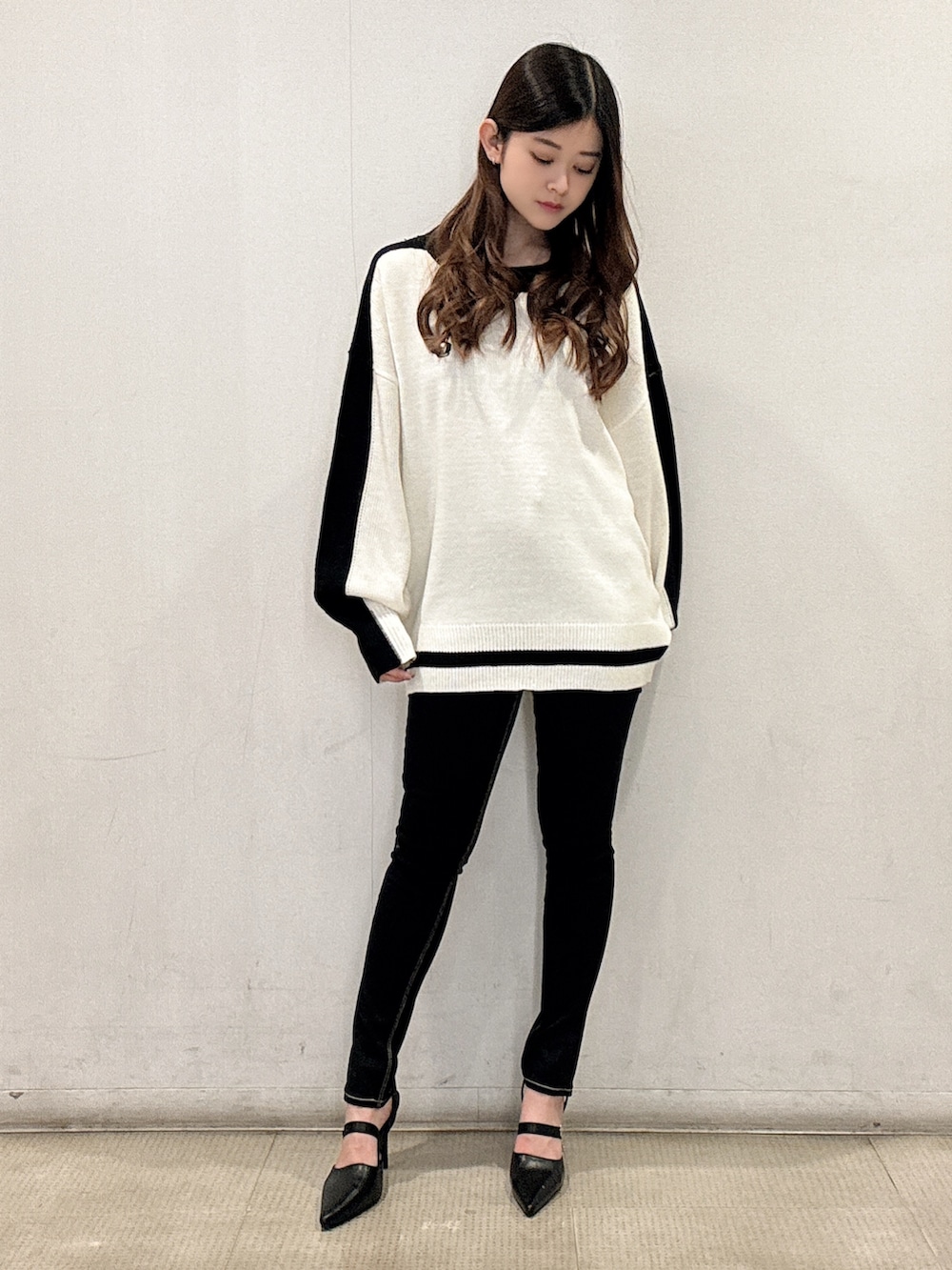 ホワイト系のニット/セーター、ブラック系のデニムパンツ、ブラック系のパンプスを着用したレディースの春コーディネートの2枚目の写真