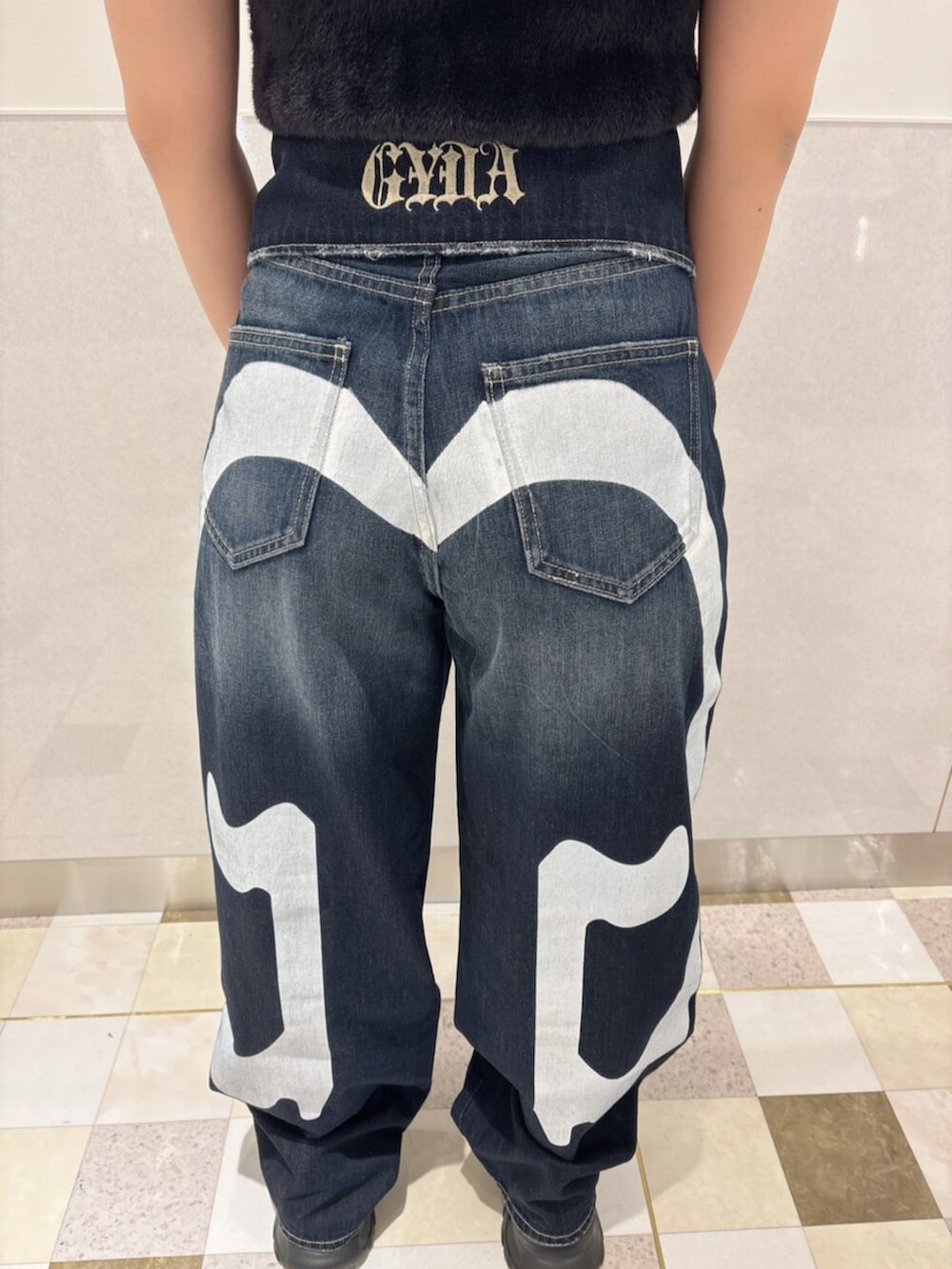 ブルー系のデニムパンツ、ブラック系のスニーカー、ブラック系のTシャツ/カットソーを着用したレディースの秋コーディネートの6枚目の写真
