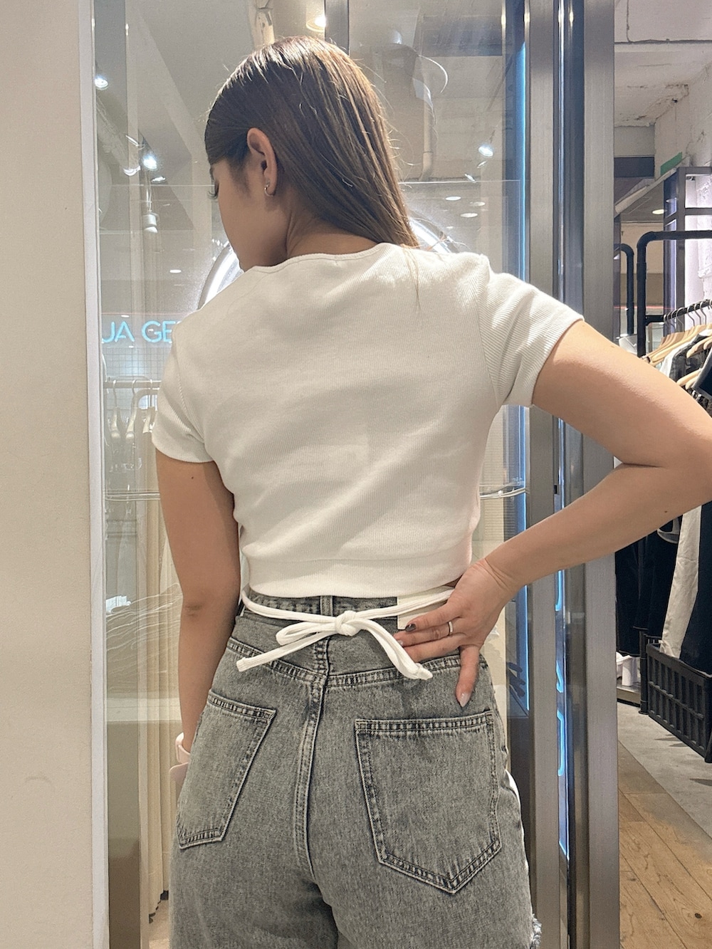 ホワイト系のTシャツ/カットソー、ブルー系のデニムパンツ、ブラック系のサンダルを着用したレディースの春コーディネートの6枚目の写真