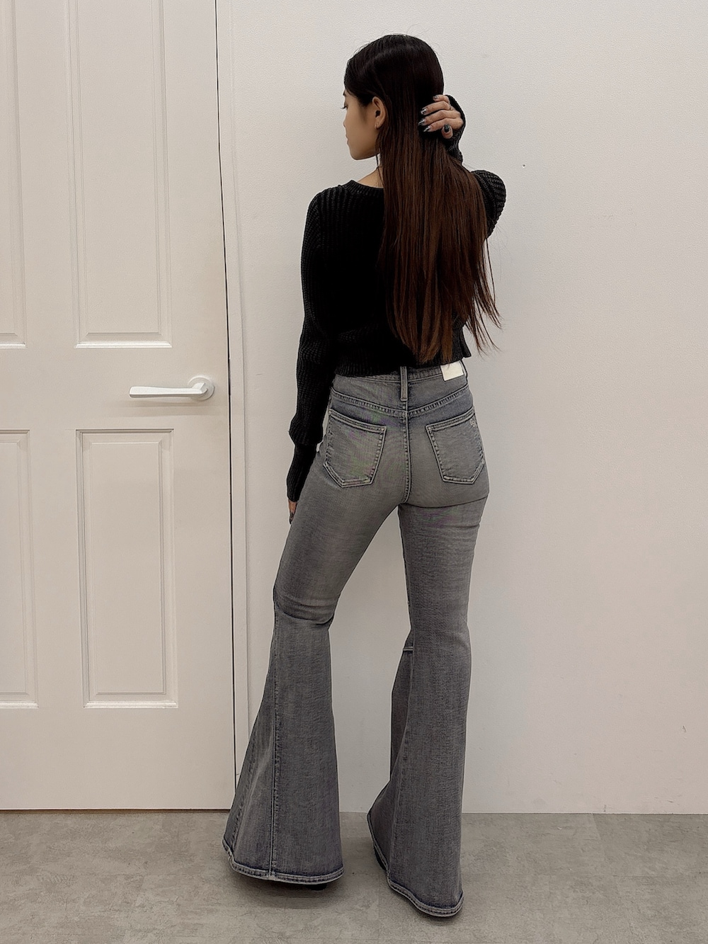 ブラック系のブーツ、ブラック系のニット/セーター、ブルー系のデニムパンツを着用したレディースの秋コーディネートの3枚目の写真