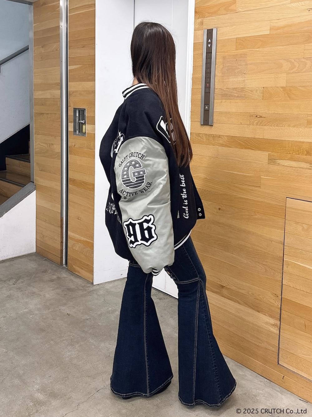 ブラック系のスタジャン、ホワイト系のニット/セーター、ブルー系のデニムパンツを着用したレディースの秋コーディネートの2枚目の写真