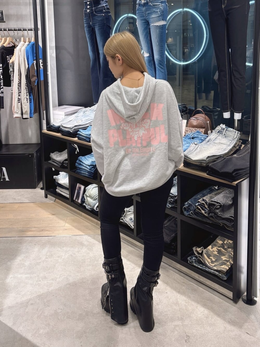 ブラック系のデニムパンツ、ブラック系のブーツ、グレー系のパーカーを着用したレディースの秋コーディネートの3枚目の写真