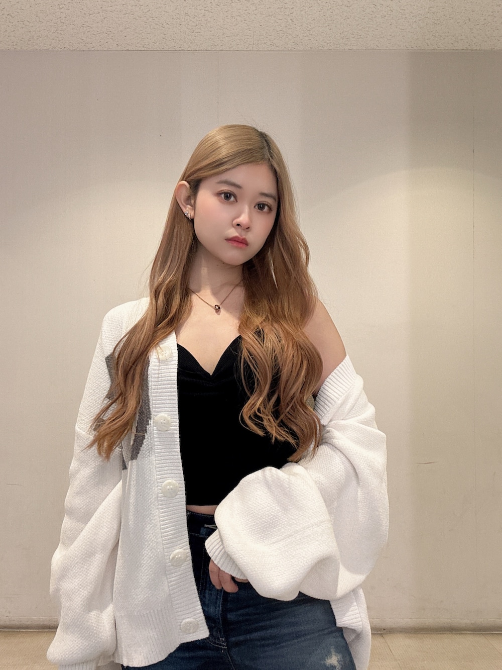 ブラック系のキャミソール、ホワイト系のカーディガン/ボレロ、ブルー系のデニムパンツを着用したレディースの春コーディネートの4枚目の写真