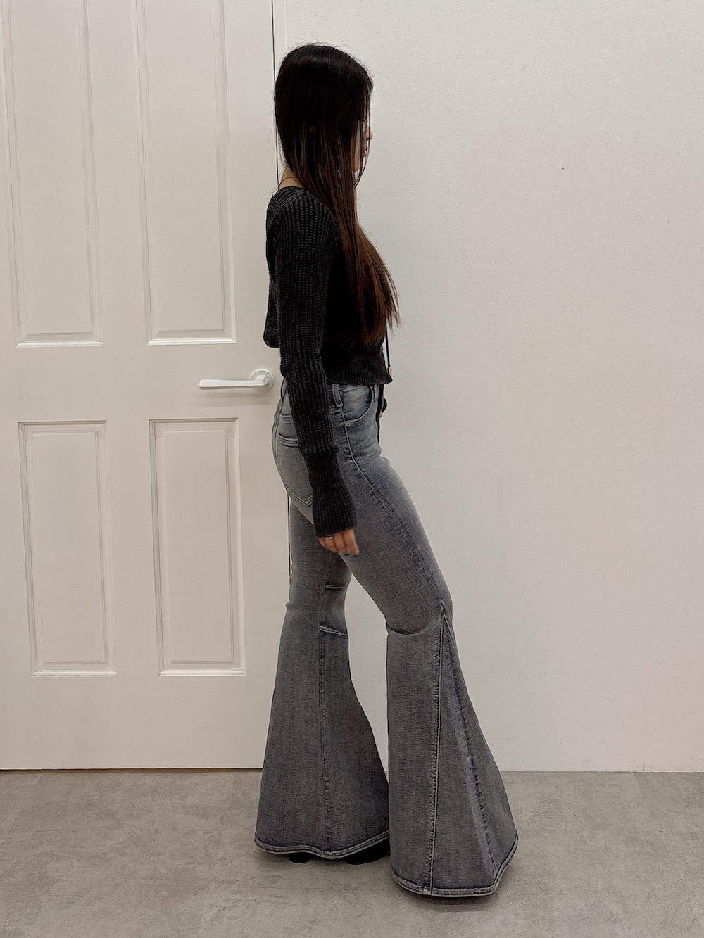 ブラック系のブーツ、ブラック系のニット/セーター、ブルー系のデニムパンツを着用したレディースの秋コーディネートの2枚目の写真