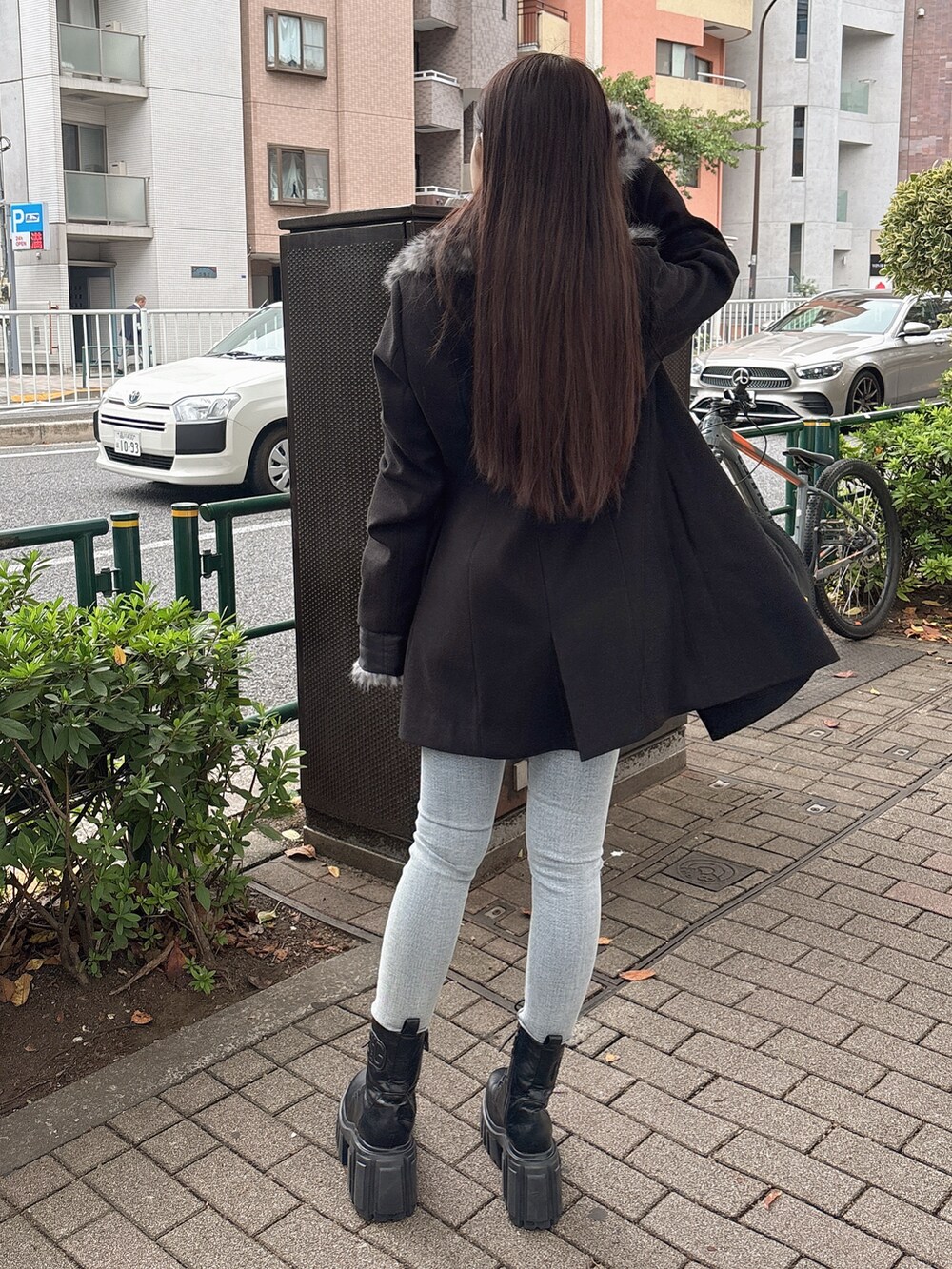 ブラック系のTシャツ/カットソー、ブラック系のチェスターコート、ブルー系のデニムパンツを着用したレディースの秋コーディネートの3枚目の写真