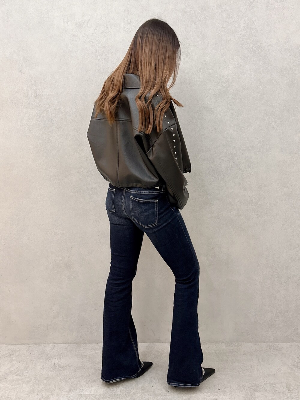 ブラック系のニット/セーター、ブラック系のライダースジャケット、ブルー系のデニムパンツを着用したレディースの冬コーディネートの2枚目の写真