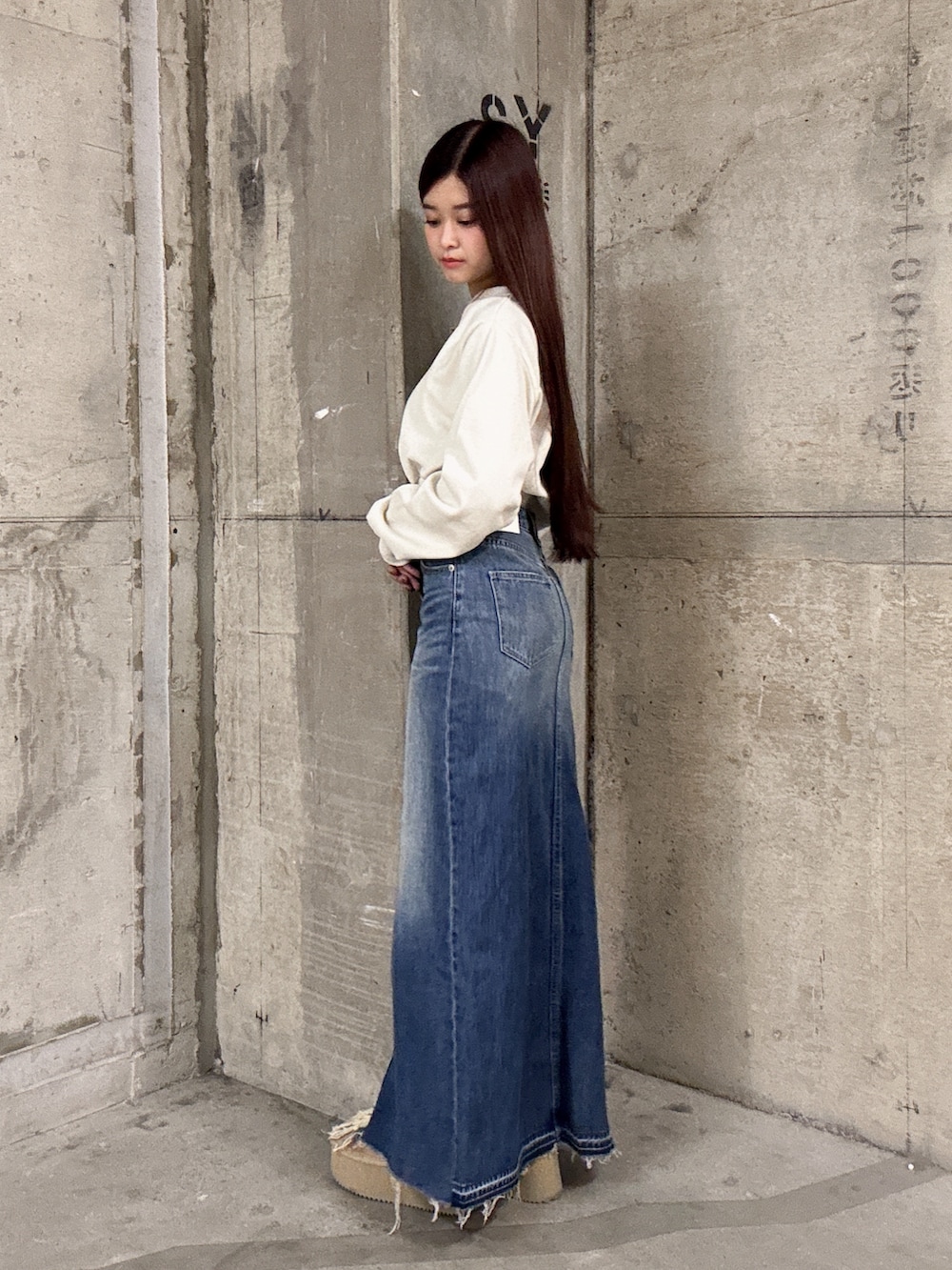 ホワイト系のスウェット、ブルー系のデニムスカート、ベージュ系のブーツを着用したレディースの秋コーディネートの2枚目の写真