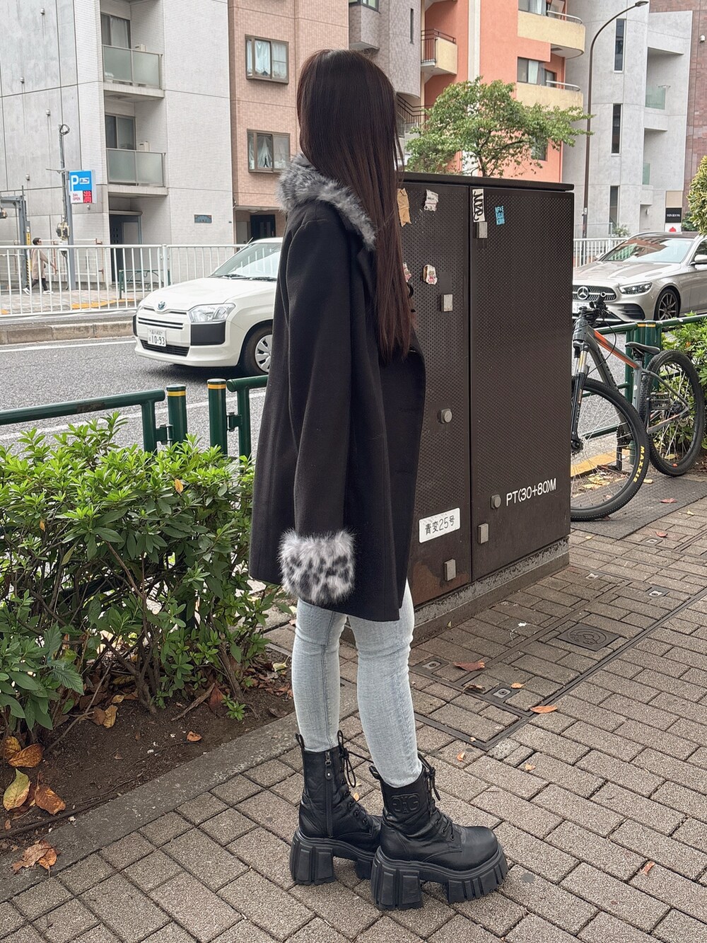 ブラック系のTシャツ/カットソー、ブラック系のチェスターコート、ブルー系のデニムパンツを着用したレディースの秋コーディネートの2枚目の写真