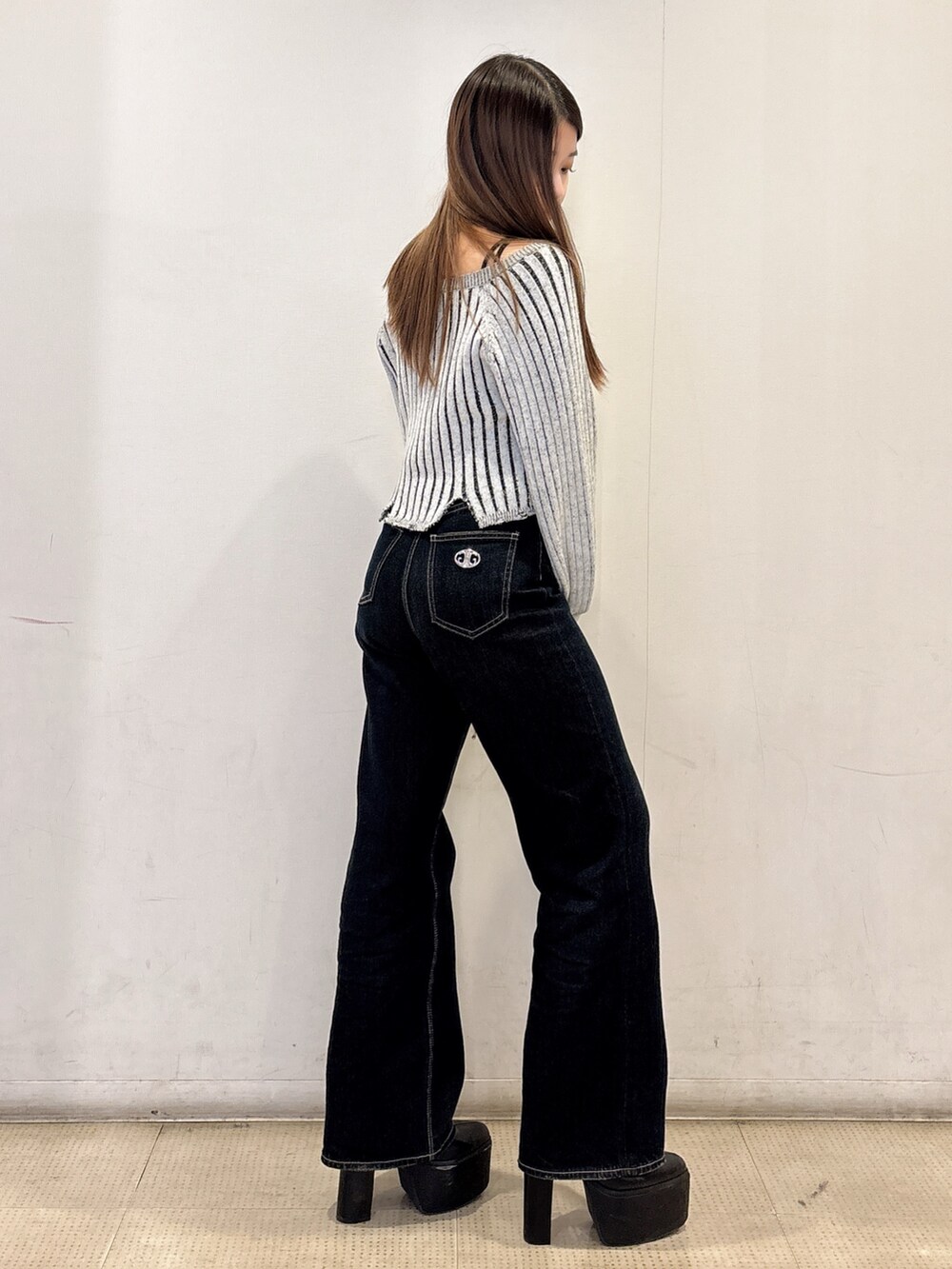 ブラック系のニット/セーター、ブルー系のデニムパンツ、ブラック系のブーツを着用したレディースの冬コーディネートの2枚目の写真