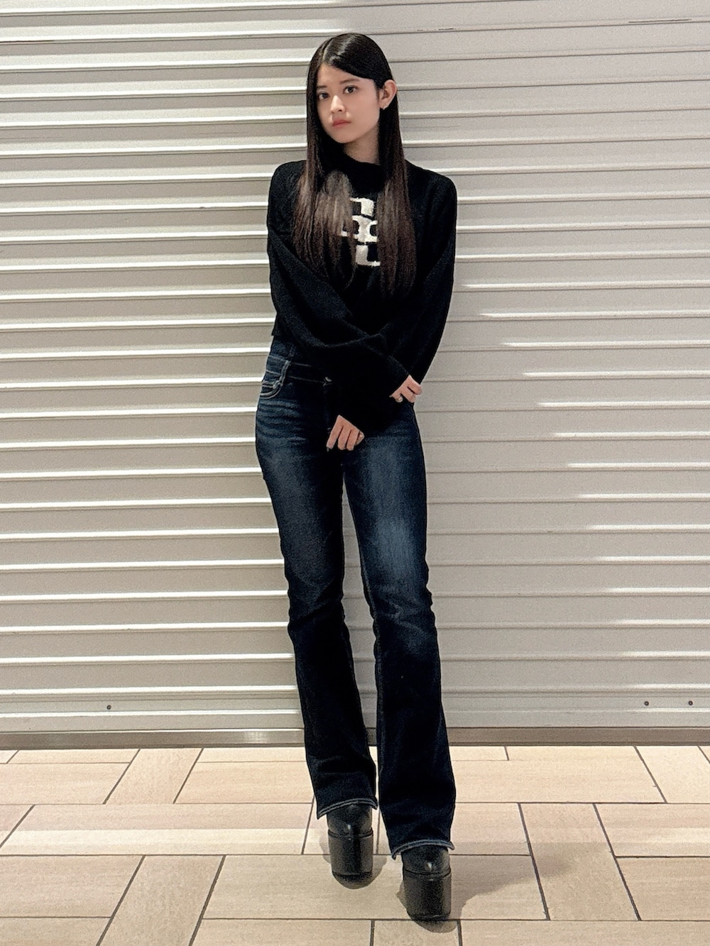 ブラック系のニット/セーター、ブルー系のデニムパンツ、ブラック系のブーツを着用したレディースの秋コーディネートの2枚目の写真