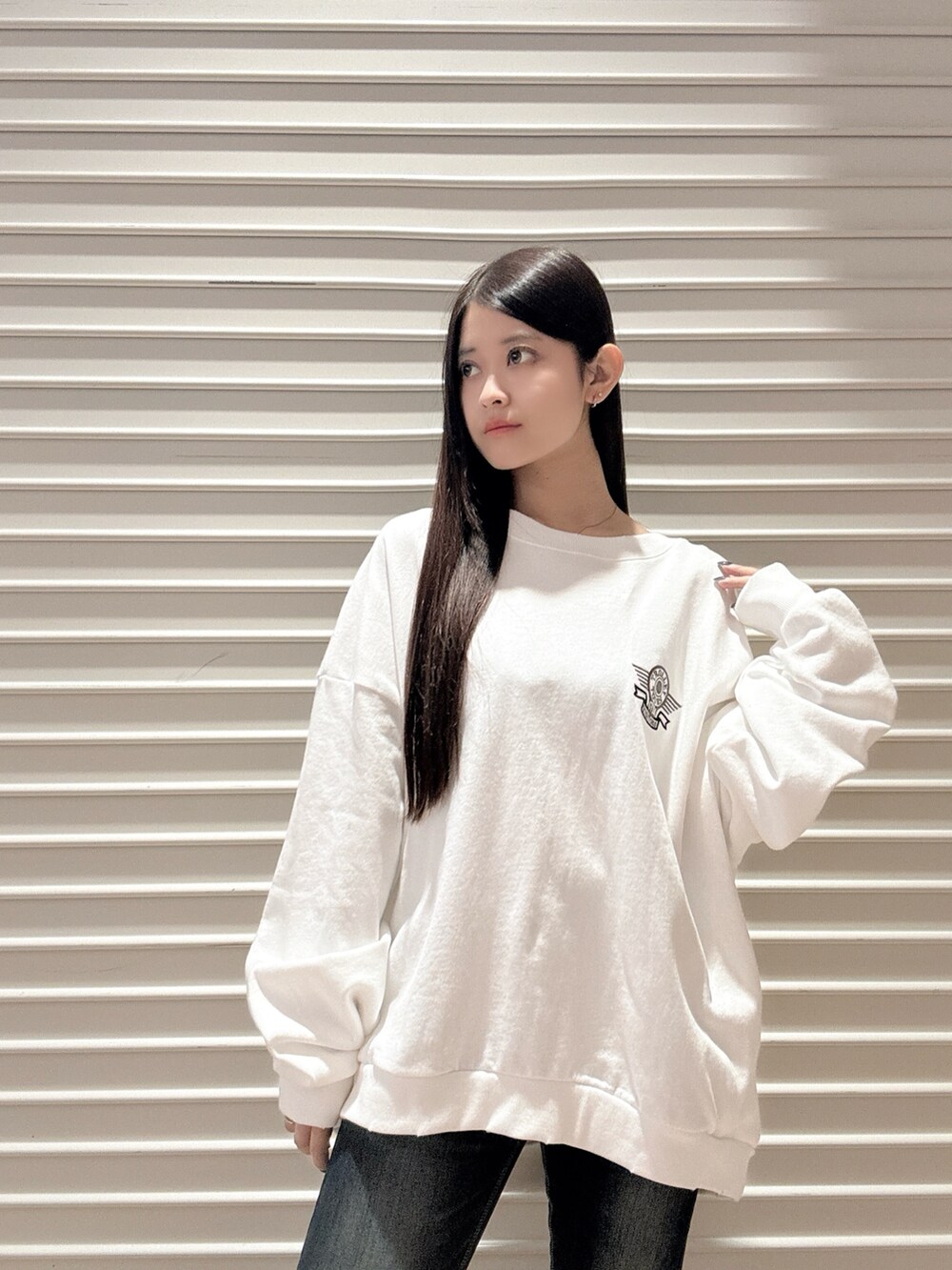 ホワイト系のスウェット、ブルー系のデニムパンツ、ブラック系のブーツを着用したレディースの秋コーディネートの4枚目の写真