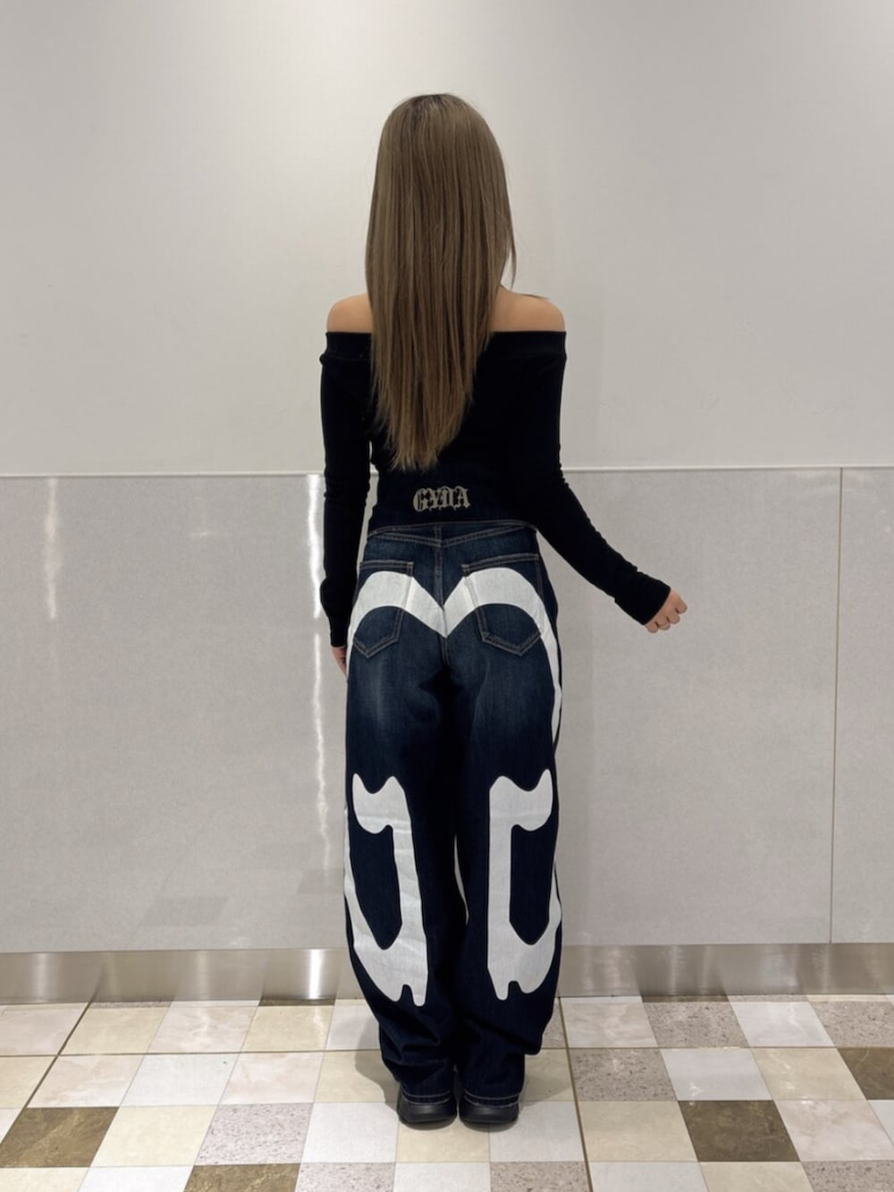 ブルー系のデニムパンツ、ブラック系のスニーカー、ブラック系のTシャツ/カットソーを着用したレディースの秋コーディネートの3枚目の写真