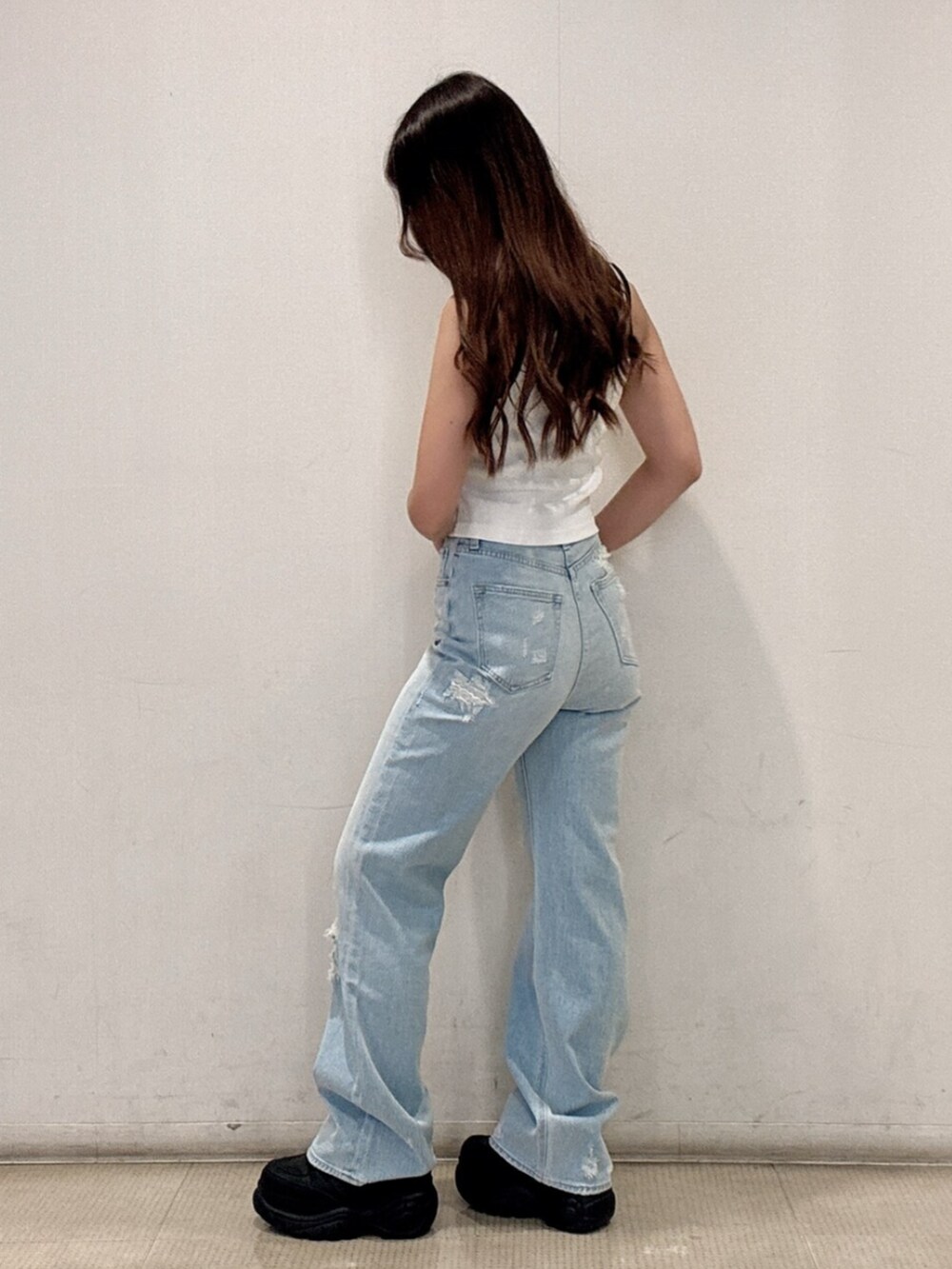 ブラック系のスニーカー、ホワイト系のタンクトップ、ブルー系のデニムパンツを着用したレディースの春コーディネートの2枚目の写真