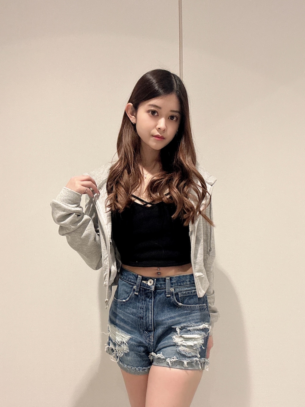 ブラック系のキャミソール、グレー系のパーカー、ブルー系のデニムパンツを着用したレディースの春コーディネートの4枚目の写真