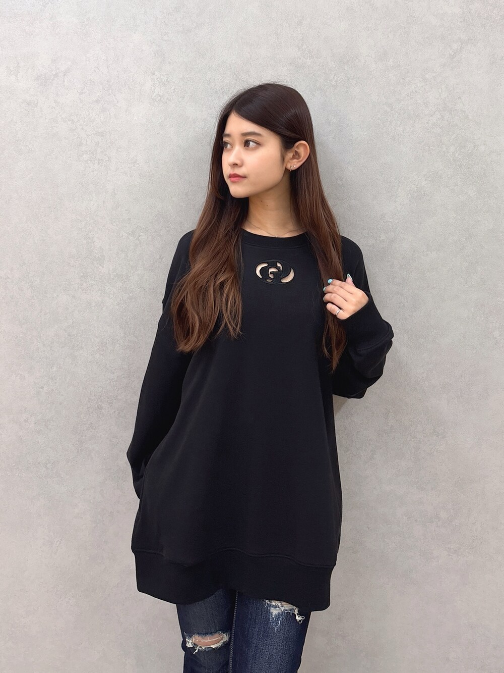 ブラック系のスウェット、ブルー系のデニムパンツ、ブラック系のサンダルを着用したレディースの夏コーディネートの4枚目の写真