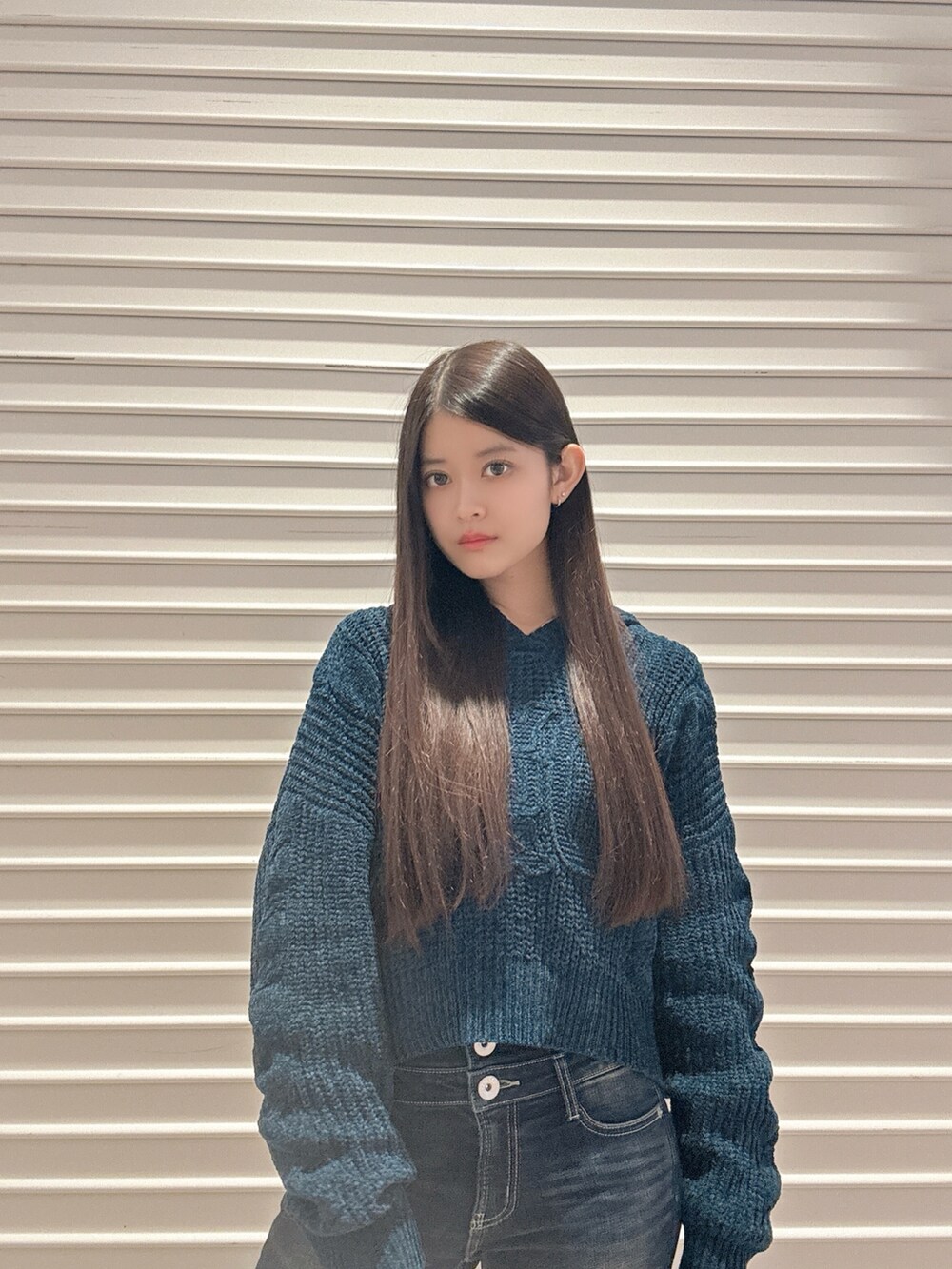 ブルー系のニット/セーター、ブルー系のデニムパンツ、ブラック系のブーツを着用したレディースの秋コーディネートの4枚目の写真