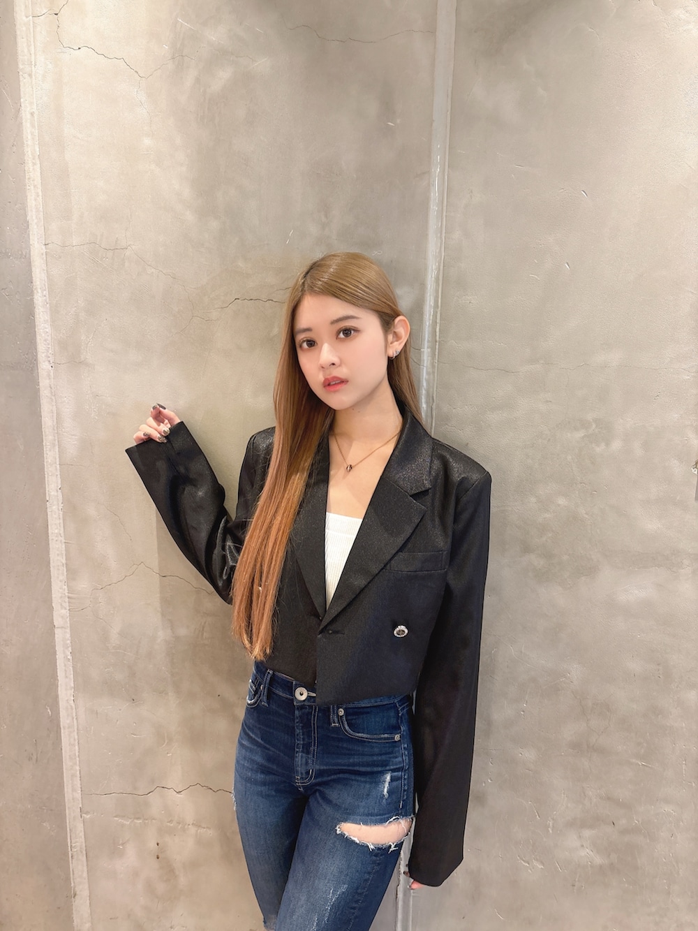 ホワイト系のキャミソール、ブラック系のテーラードジャケット、ブルー系のデニムパンツを着用したレディースの春コーディネートの4枚目の写真